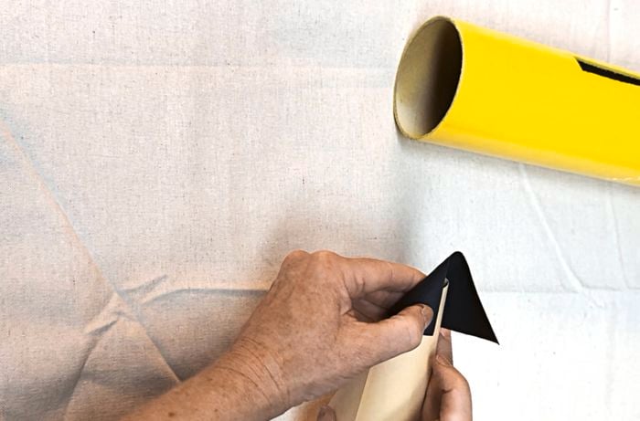 Hands attaching a black tip to a light-coloured cone, with a yellow cylinder in the background.