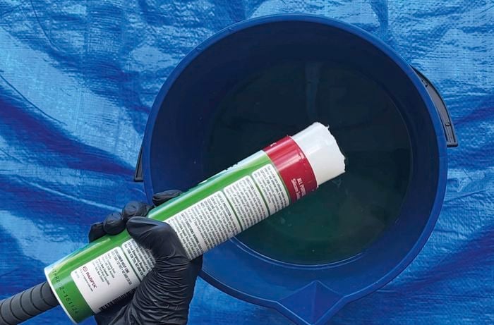 Blue trap with bucket and someone pouring in silicone into soapy water.