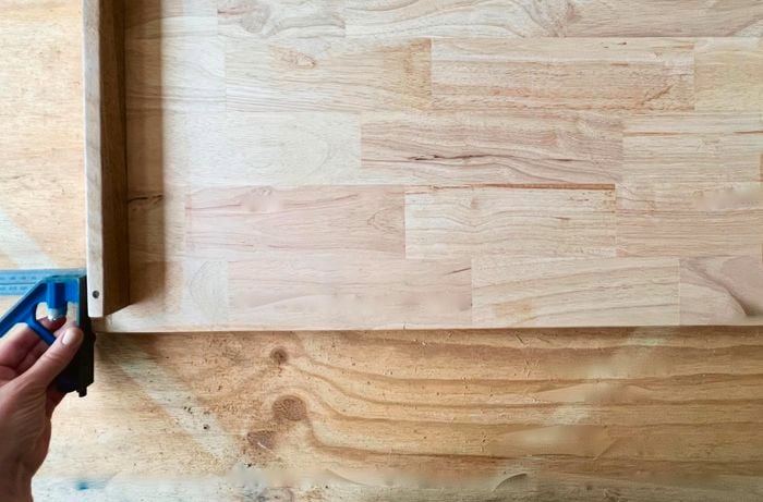 A person uses a combination square to measure a D.I.Y. timber cabinet top