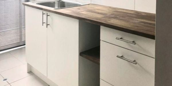 A laundry with white cabinets and a timber benchtop