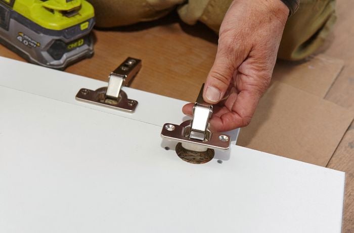 Person attaching hinges to cupboard doors