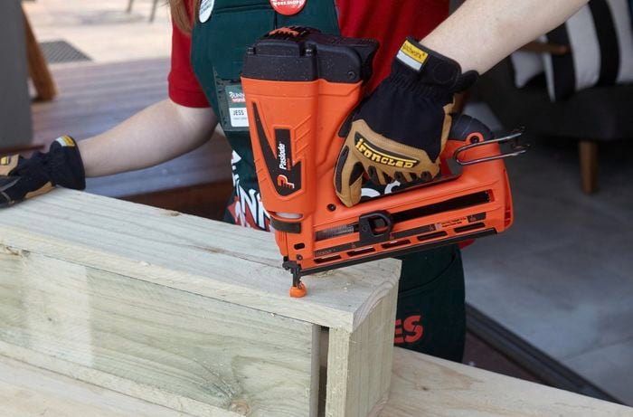 Bunnings team member Jess joining lengths of timber with a nail gun