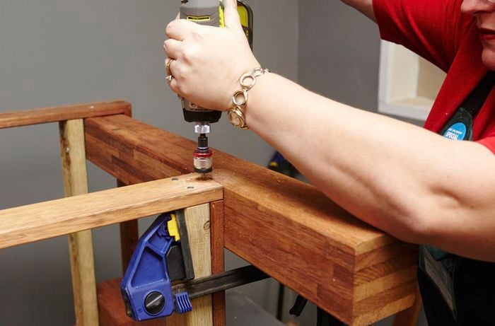 Person joining frames together with drill.