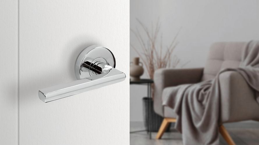 A stainless-steel door handle on a white door from Delf