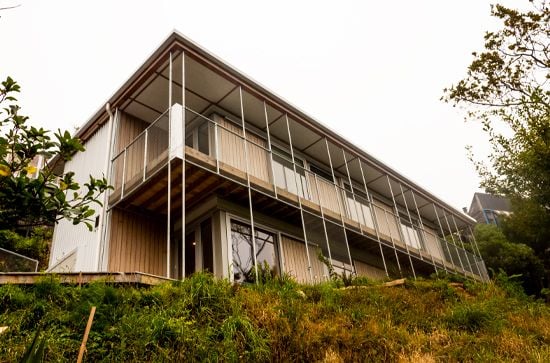 A two-story sustainable house with timber panelling on a hillside