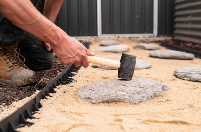 A person is laying stepping stones in the pathway.