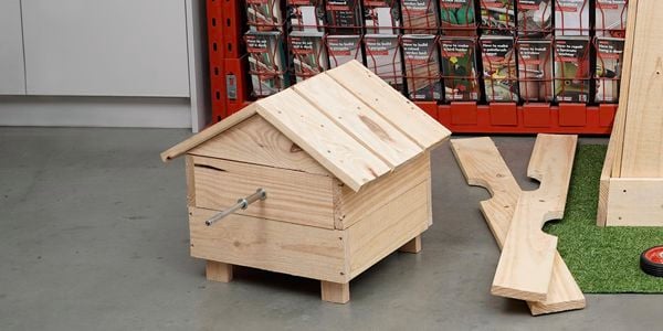 Timber pieced together to form a vertical box and a small timber house.