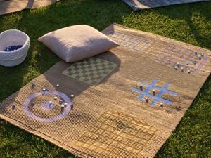 Kids playmat set up outside with cushion and game accessories.
