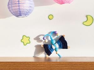 A D.I.Y. Bluey craft Flappy project sits on a timber shelf with a star, moon, planet and two Bluey lanterns about it.