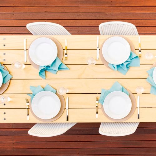 Top view of a clear finish on a outdoor timber table decorated with dinnerware and cutlery