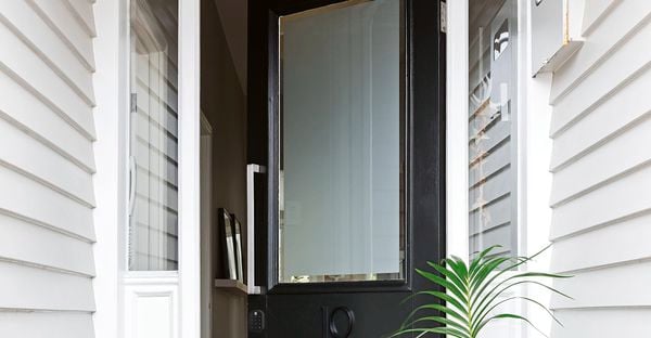 Black front entry door of a home featuring a frosted glass panel and a smart door lock.