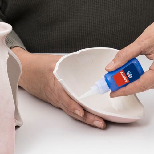 Person repairing vase with Loctite Super Glue.