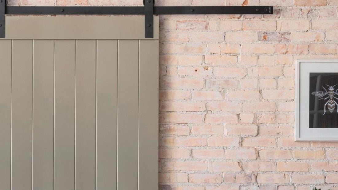 Sliding barn door installed on light red brick wall.