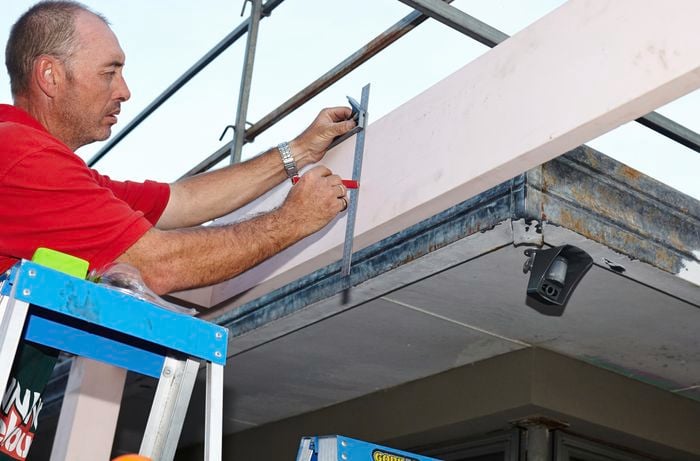 Person marking where rafters would go on carport frame.