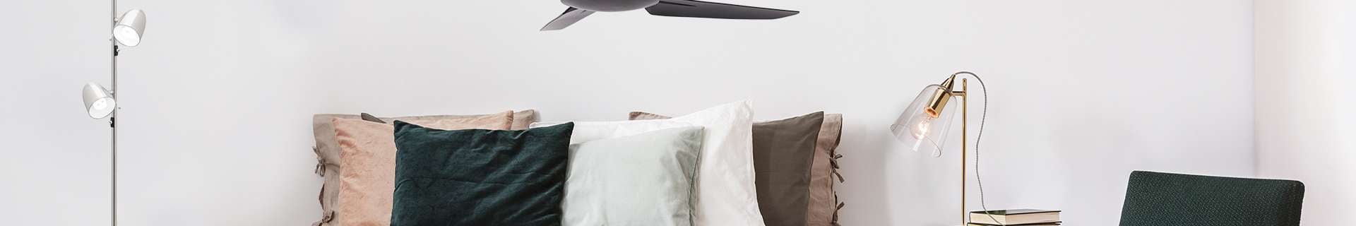 Bedroom with monochrome bedding, lamp and ceiling fan.