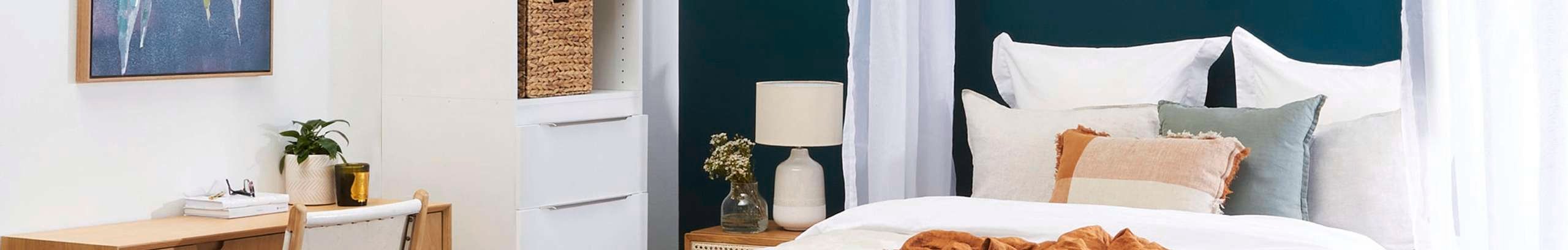 bedroom with linen bedding, jute rug, dark green feature wall and desk.