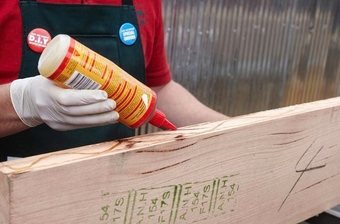 A person applying glue to the side of a piece of hardwood
