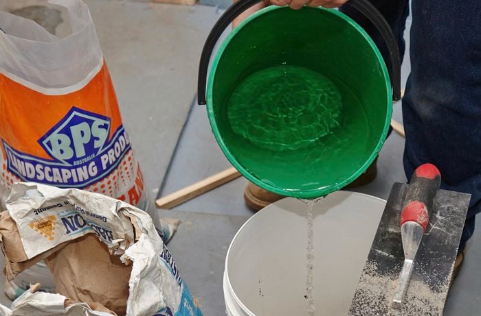 A person pouring water into a mixing bucket