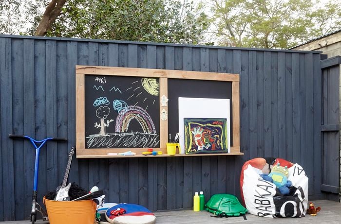 Toddler activity chalkboard hanging on fence.