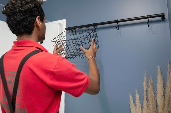 A Bunnings team member hanging a metal basket on a mounted bathroom rail