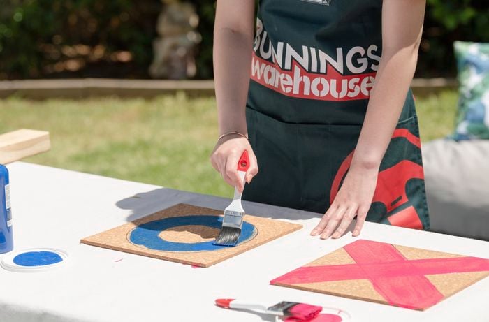 Person painting circle on corkboard.
