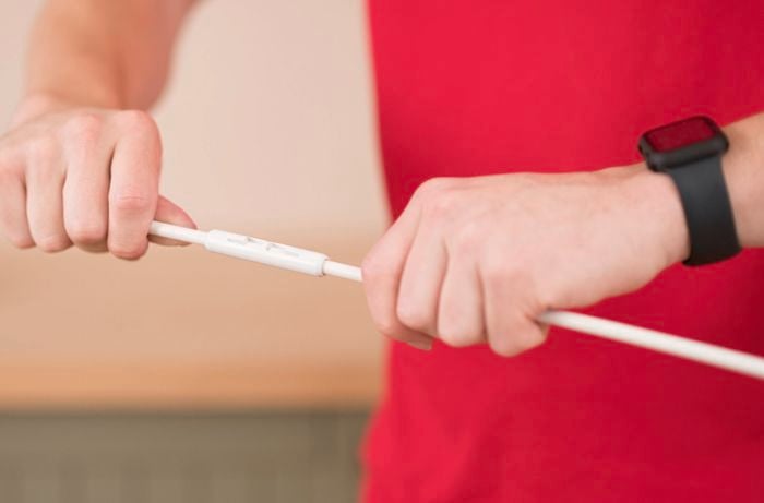 A person in a red T shirt holding a cable.