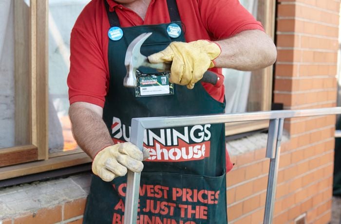 A person hammering the corner of metal frame
