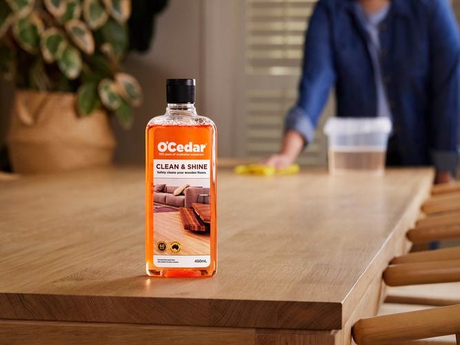 A bottle of O'Cedar clean & shine polish on a Wooden table.