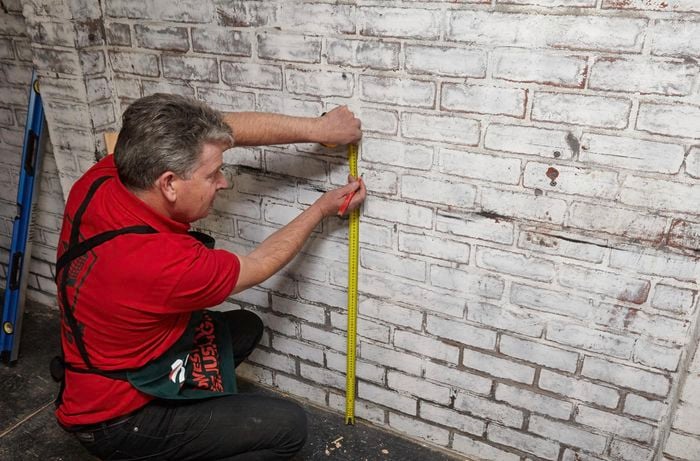 Person measuring against a wall.