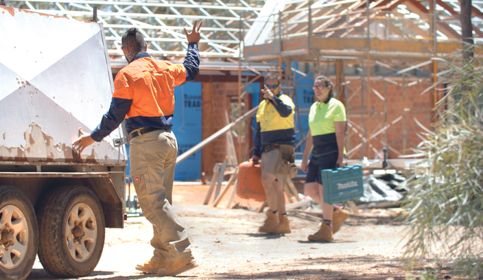 job site with tradies waving to each other as they part ways 