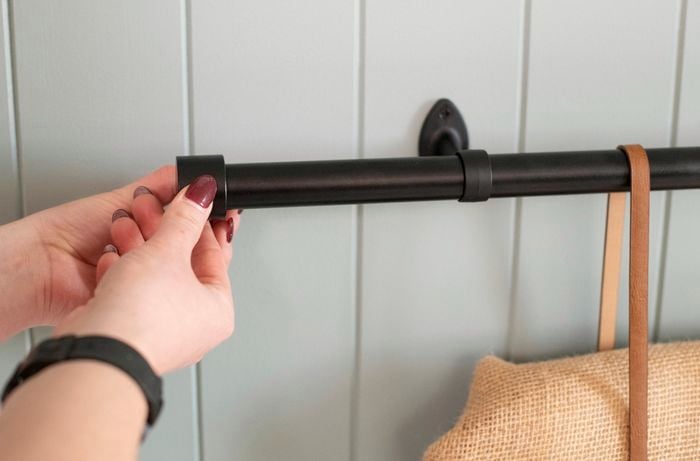 Person attaching end piece cap to curtain rod.