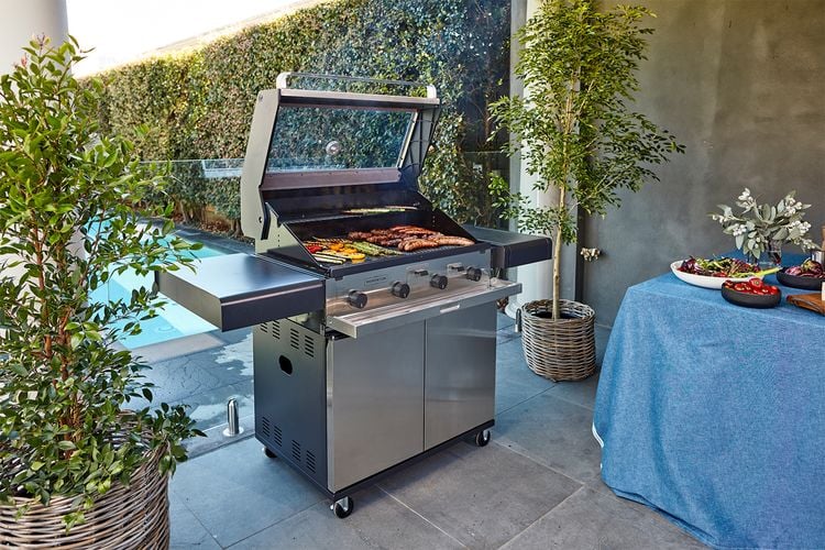 A stainless steel barbecue cooking a variety of meats and vegetables