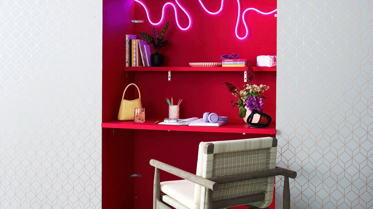 Study nook with red bookshelf, chair, neon pink LED lights and bookshelf decorations.