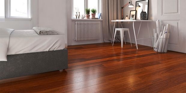 A bed and a desk in a bedroom with flooring boards.