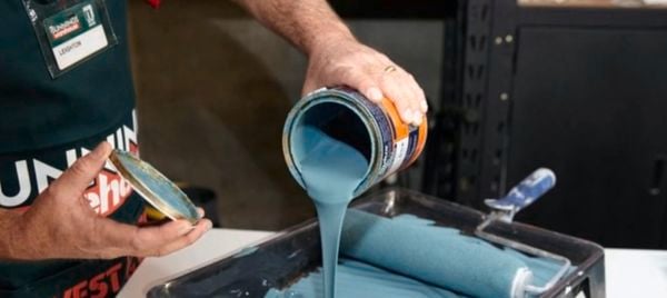 A person pouring blue paint into a paint tray.