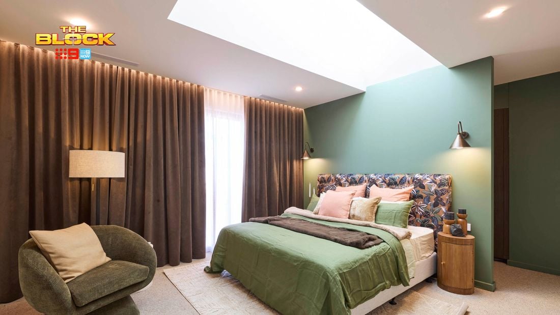Bedroom with green accent wall, patterned headboard, and earthy decor.