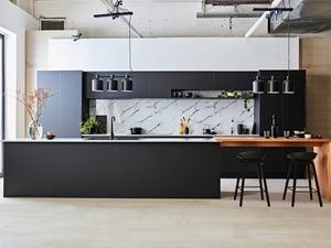 Kitchen with black cabinets, black benchtops and marble splashback.
