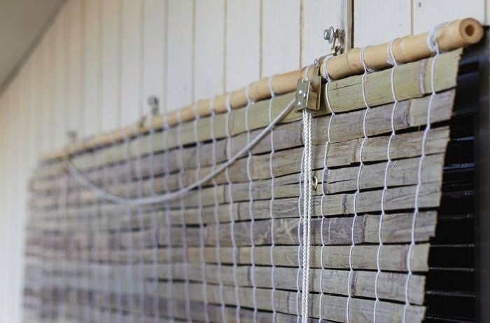 A close-up of a bamboo blind fixed to an external wall with a screw