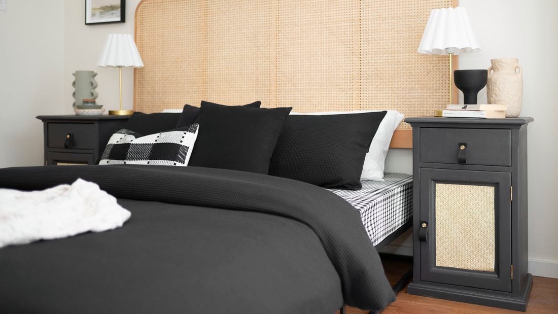 The room has a bed with black bedding and lamps on both bedside tables.