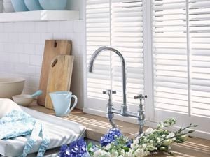 Close up of a kitchen sink and white shelves filled with blue and white dinnerware.