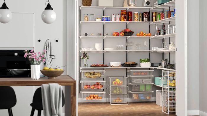 Kitchen with an open pantry full of items in it, a table with chairs sitting at it, an over and cupboards in it.