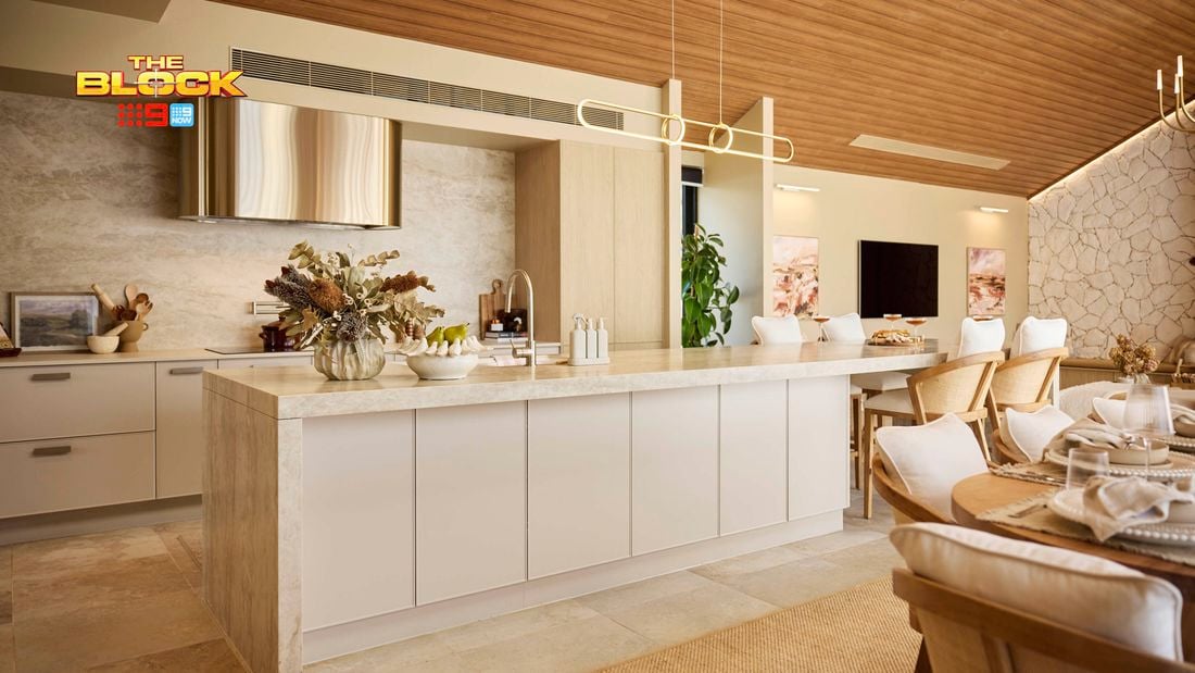 Modern kitchen with marble island, stone feature wall, and dining table.