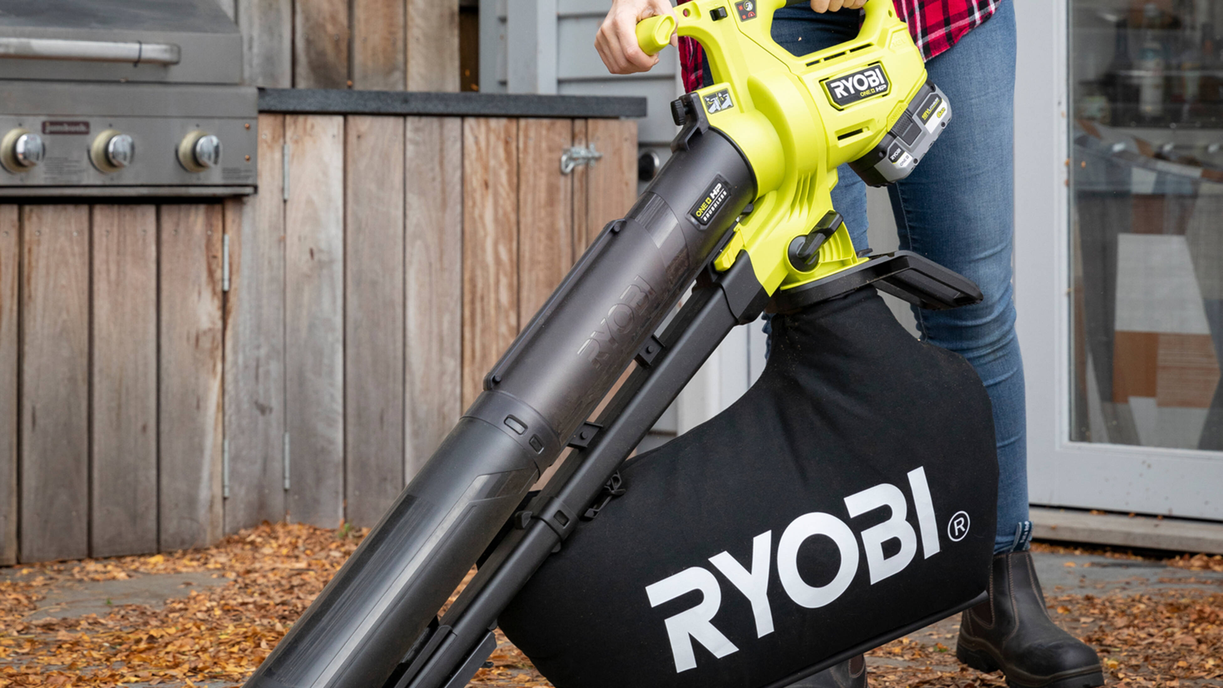 A close up shot of a person using a Ryobi leaf blower and vacuum