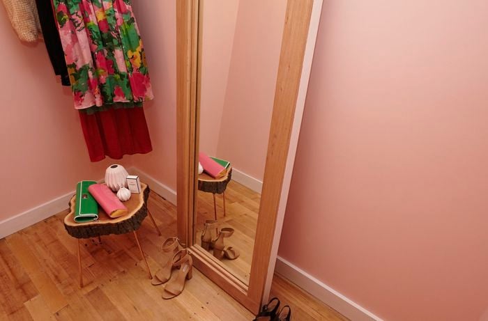 A narrow dressing room with clothes, shoes and a full-length mirror in a timber frame