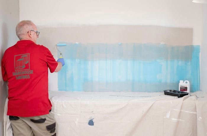 Apply primer to the wall to help the adhesive bond properly