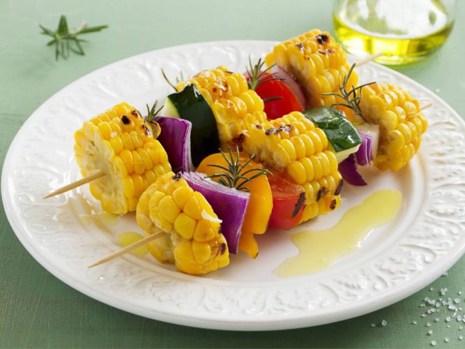 Sweet corn kebab with capsicum, onion, tomato and zuchinni served on white plate with rosemary garnish