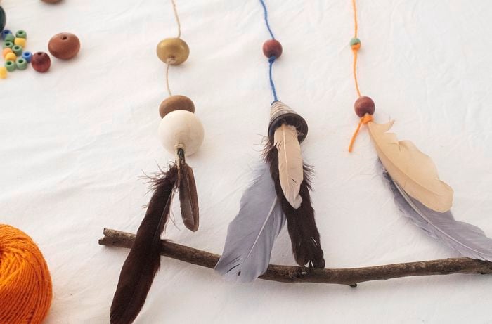 A completed nature hanging with feathers, beads and three pieces of string.
