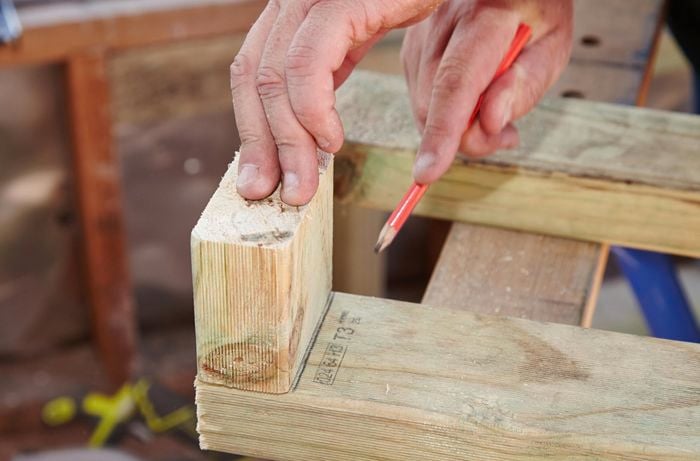 A person marking a line on a piece of framing timber using an offcut