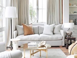 Living room with grey interior theme, a patterned grey rug with couch on top and two lamps beside the couch.