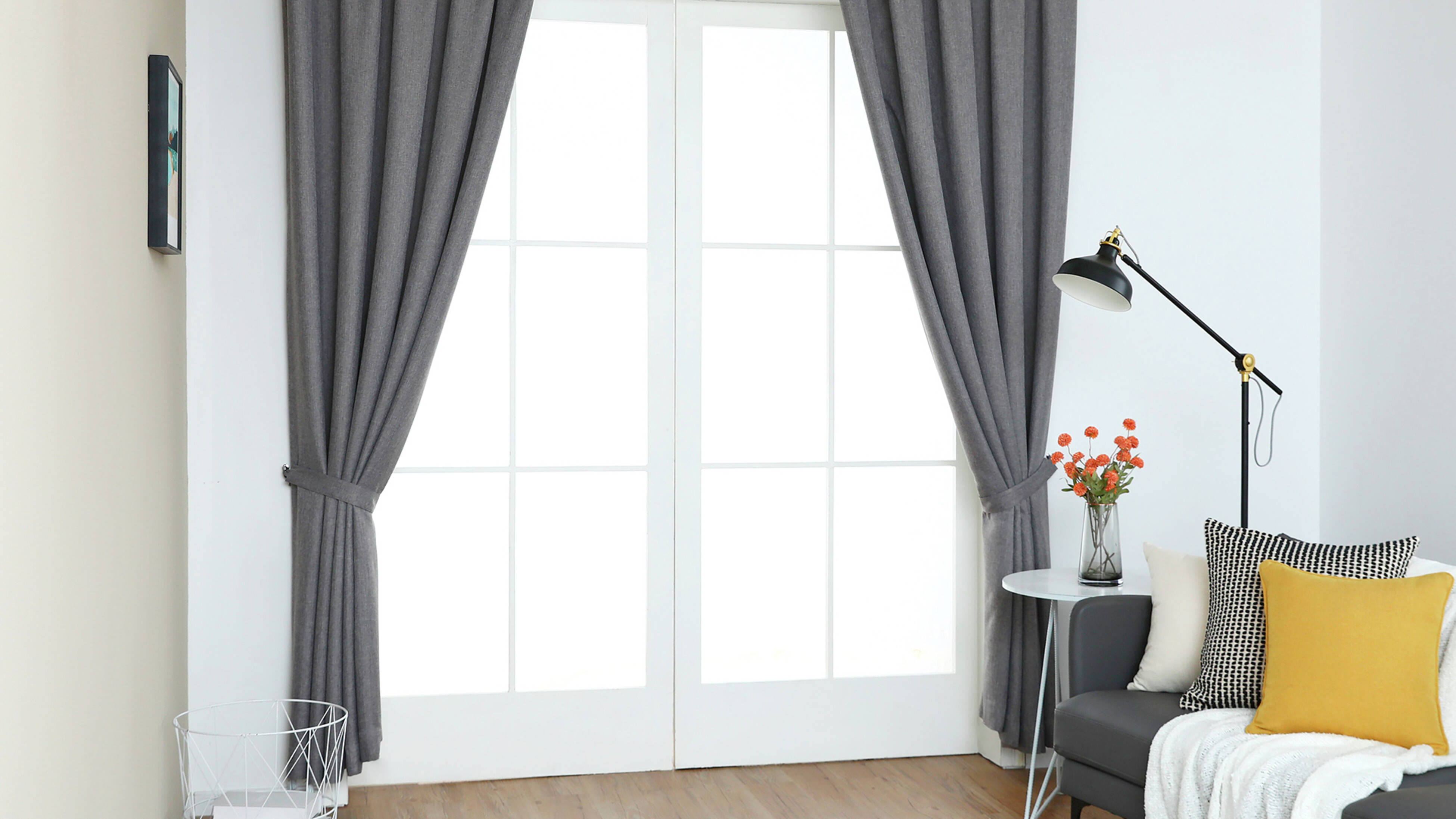  Dark grey, pencil pleat, room darkening curtains on a window, with a sofa, side table, and floor lamp in a living room setting